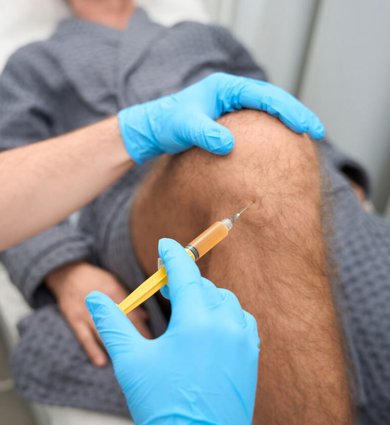 Experienced-doctor-taking-a-biopsy-sample-from-a-male-knee-for-stem-cell-therapy